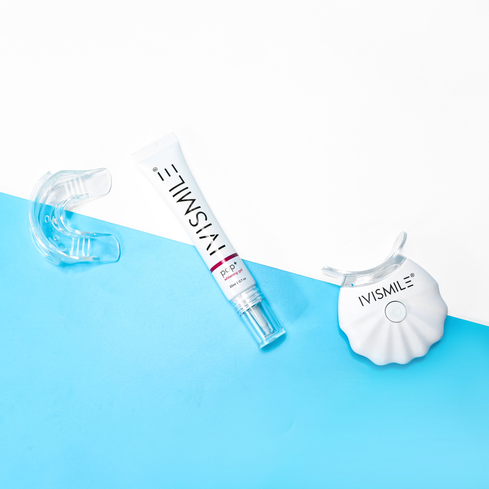 IVISMILE Wireless LED Teeth Whitening Kit components laid out on a split white and blue background. Includes a clear silicone mouth tray, a tube of whitening gel labeled "pap+", and a white LED light device with the IVISMILE logo.